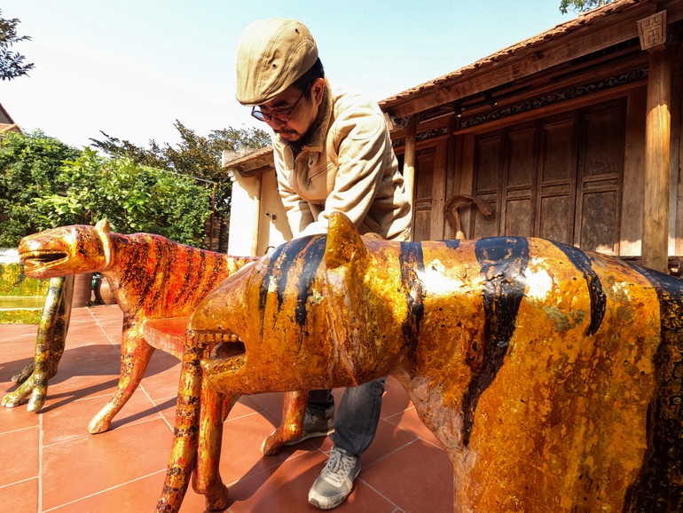 Nghệ nhân Nguyen Tan Phat đứng bên cạnh các tác phẩm chạm khắc lấy cảm hứng từ hổ tại Hà Nội, Việt Nam (Ảnh: Reuters).